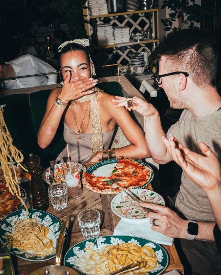 Guests laughing around a table with pizza and pasta